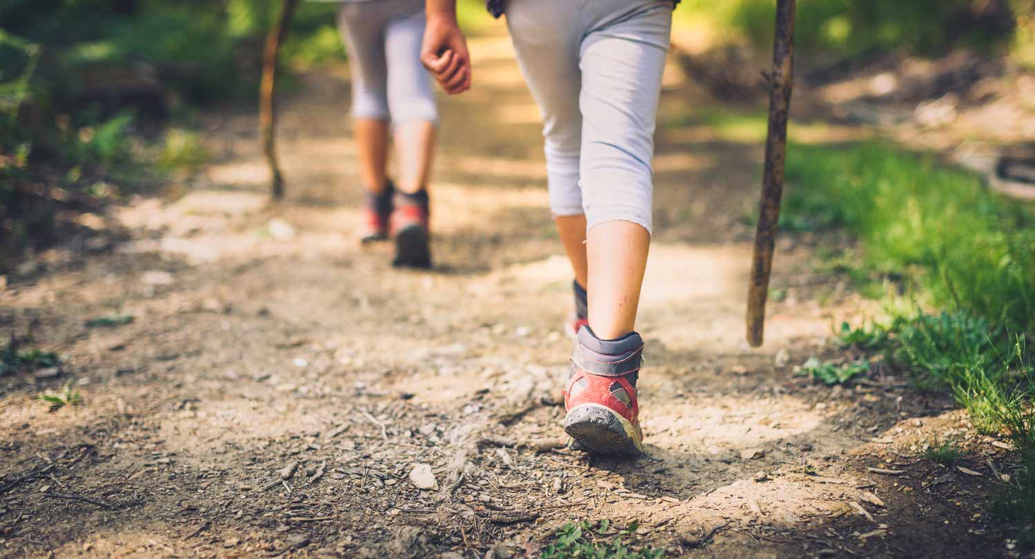 2 people from waist down walking down dirt trail